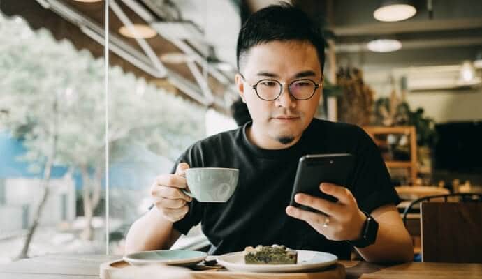 man enjoying meal looking at cell phone launching Norton 360 Standard.